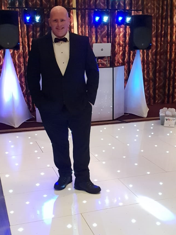 DJ in tux standing on LED disco dance floor for hire
